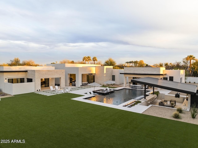 back of property with a yard, stucco siding, a patio area, and an infinity pool