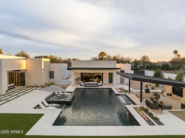 back of house featuring an outdoor living space with a fireplace, stucco siding, an outdoor pool, and a patio