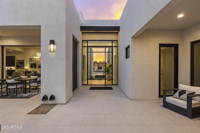exterior entry at dusk featuring a patio area and stucco siding