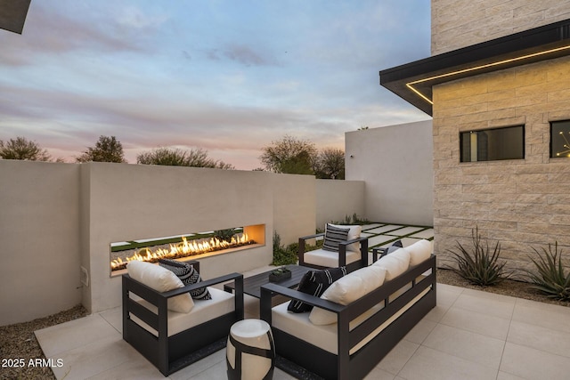patio terrace at dusk with an outdoor living space with a fireplace