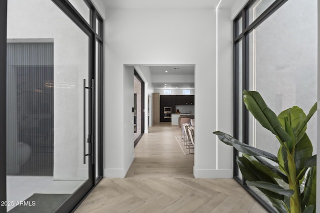 hall with baseboards and a towering ceiling