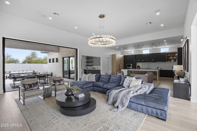 living area with recessed lighting, visible vents, a wealth of natural light, and light wood-style floors