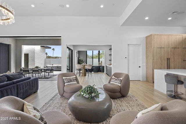 living room featuring recessed lighting, a chandelier, visible vents, and light wood-style flooring