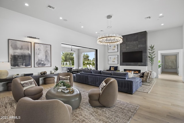 living area featuring recessed lighting, visible vents, a large fireplace, and light wood finished floors