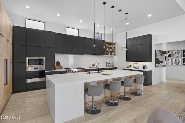 kitchen with appliances with stainless steel finishes, a sink, dark cabinetry, a breakfast bar area, and modern cabinets
