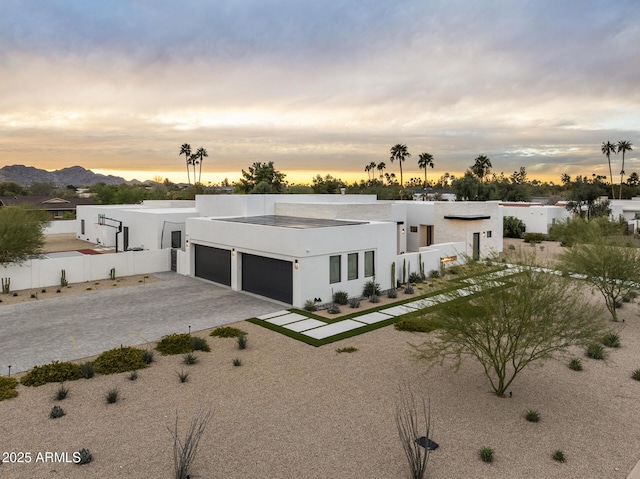 view of front of property with a garage, fence, stucco siding, and driveway