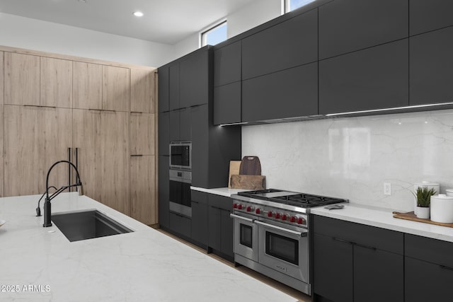 kitchen with dark cabinets, a sink, appliances with stainless steel finishes, and modern cabinets