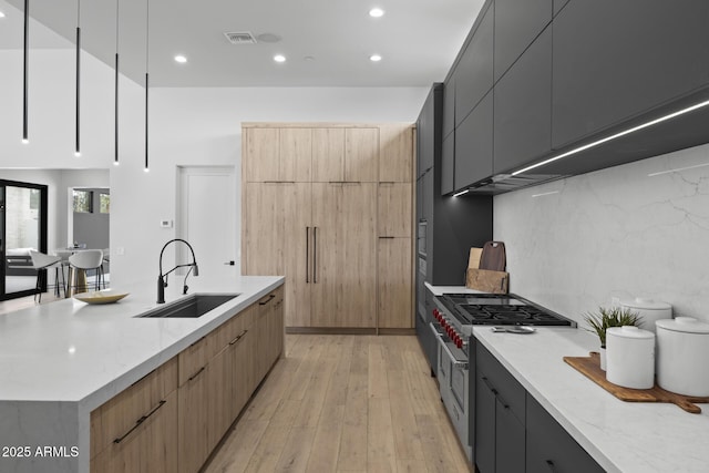 kitchen featuring a sink, light wood finished floors, range with two ovens, recessed lighting, and modern cabinets