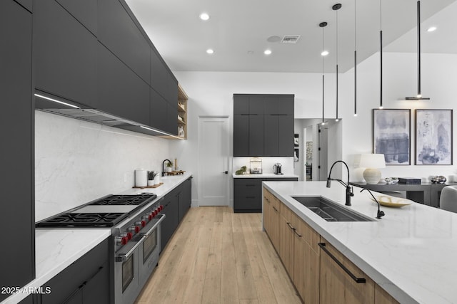 kitchen with dark cabinetry, range with two ovens, a sink, and modern cabinets