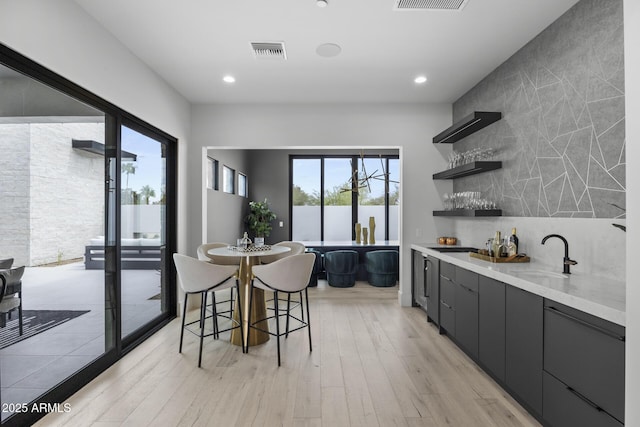 kitchen with a sink, modern cabinets, light wood-style floors, and visible vents