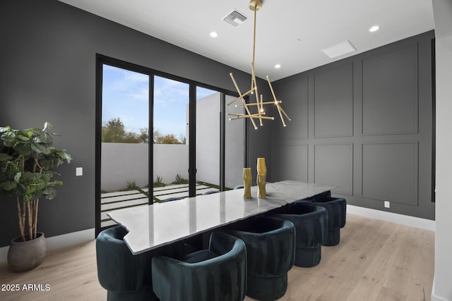 dining area with visible vents, light wood-style floors, a decorative wall, and a notable chandelier