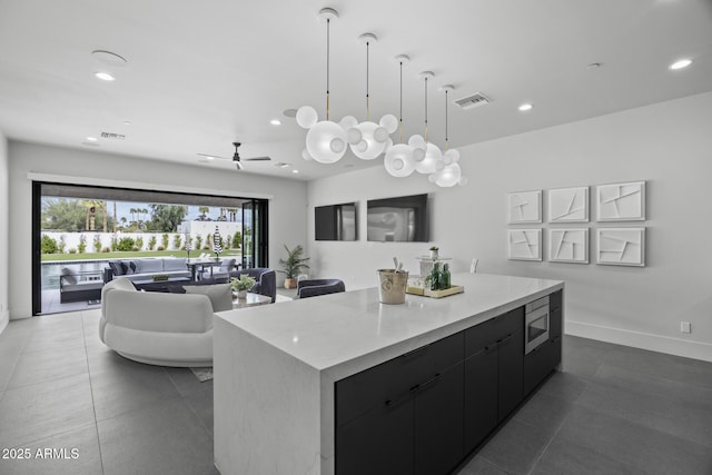 kitchen with visible vents, a center island, modern cabinets, dark tile patterned flooring, and dark cabinetry