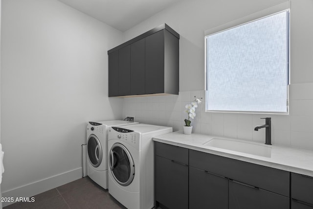 clothes washing area with a sink, dark tile patterned flooring, independent washer and dryer, and cabinet space