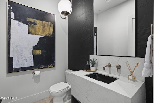 bathroom with vanity, baseboards, backsplash, and toilet