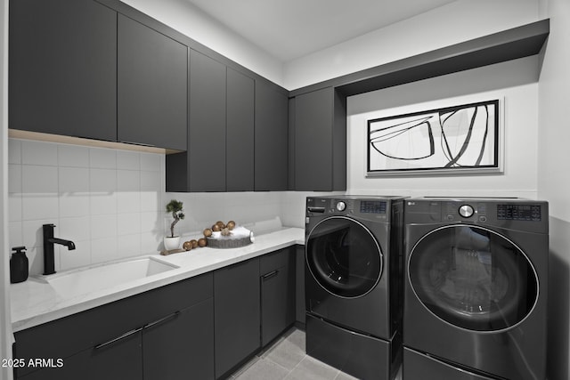 clothes washing area featuring a sink, light tile patterned floors, cabinet space, and washer and clothes dryer