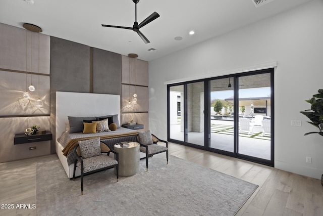 bedroom with light wood-style floors, a towering ceiling, visible vents, and access to exterior
