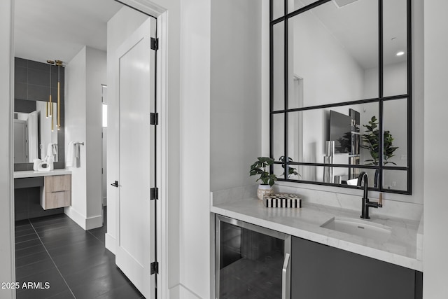 hall featuring dark tile patterned floors, a sink, baseboards, and wine cooler