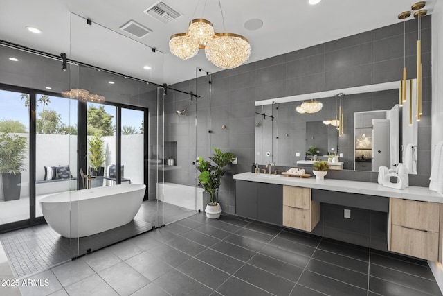 bathroom with a freestanding bath, a notable chandelier, vanity, tile patterned floors, and a shower stall