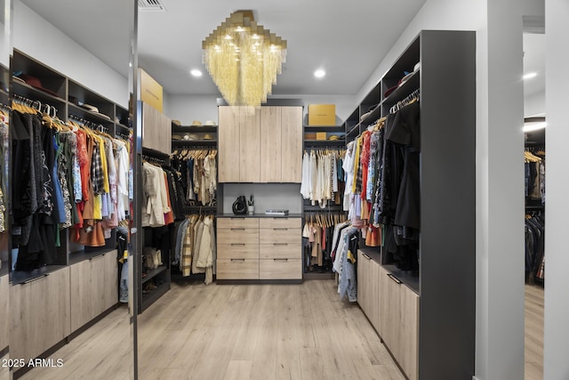 spacious closet with an inviting chandelier and light wood finished floors