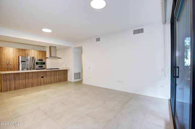 kitchen with kitchen peninsula, appliances with stainless steel finishes, a breakfast bar area, and wall chimney range hood