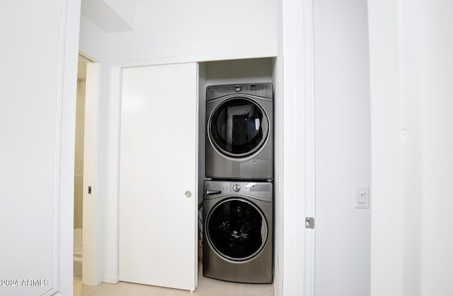 laundry area with light tile patterned floors and stacked washer / drying machine