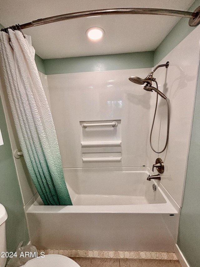 bathroom featuring shower / bathtub combination with curtain and toilet