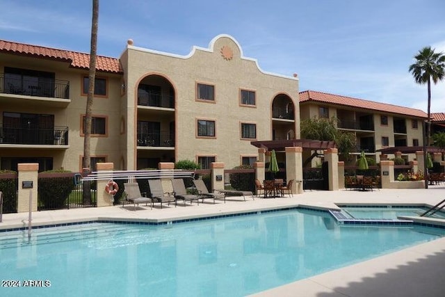 view of swimming pool featuring a pergola and a community hot tub