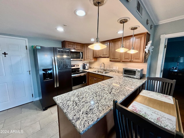 kitchen with light stone countertops, sink, kitchen peninsula, pendant lighting, and appliances with stainless steel finishes