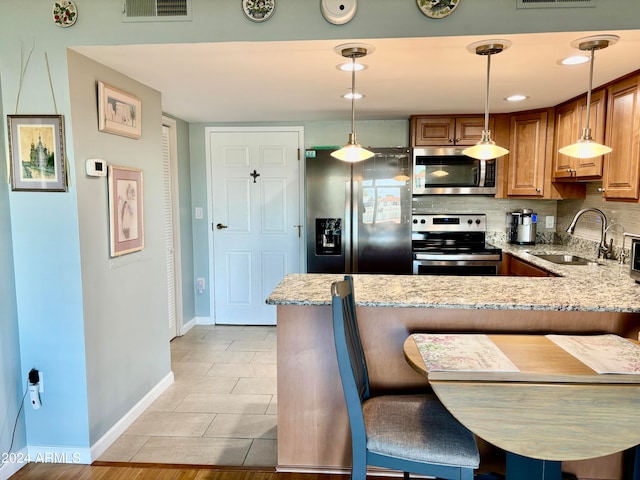 kitchen with hanging light fixtures, kitchen peninsula, a breakfast bar area, and appliances with stainless steel finishes