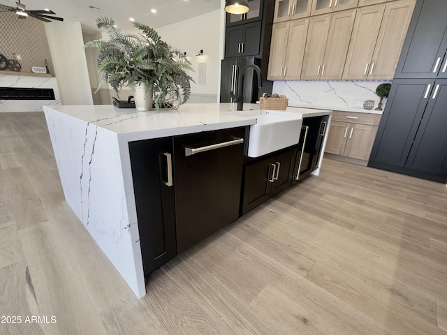 kitchen featuring a sink, light wood finished floors, freestanding refrigerator, an island with sink, and recessed lighting