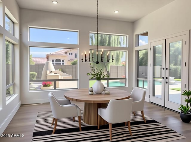 dining area with a chandelier, plenty of natural light, wood finished floors, recessed lighting, and french doors