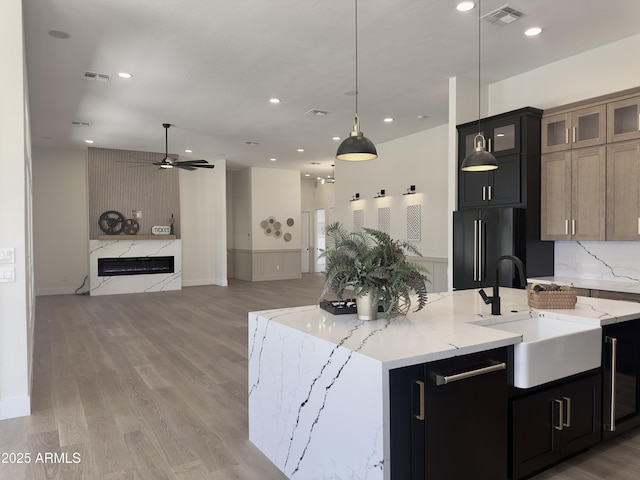 kitchen with high end black refrigerator, a sink, ceiling fan, open floor plan, and pendant lighting