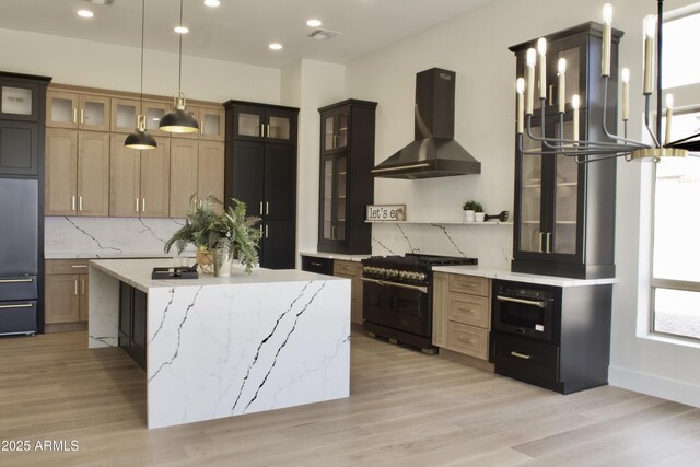 kitchen with stainless steel gas range oven, wall chimney exhaust hood, built in fridge, decorative backsplash, and light wood finished floors