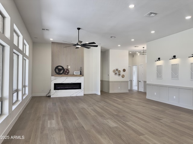 unfurnished living room featuring a high end fireplace, recessed lighting, wood finished floors, and a ceiling fan