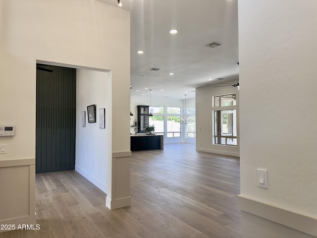 hallway with light wood finished floors, recessed lighting, and baseboards