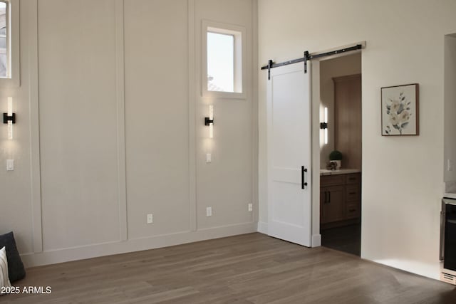 foyer featuring a barn door, wood finished floors, and baseboards