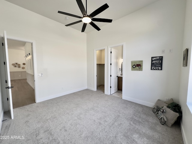 unfurnished bedroom featuring light colored carpet, a spacious closet, connected bathroom, and baseboards