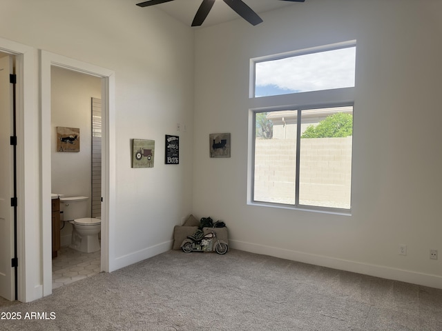 carpeted empty room with a ceiling fan and baseboards