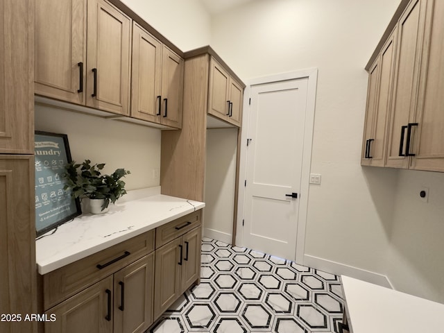 laundry room featuring cabinet space, electric dryer hookup, light flooring, and baseboards