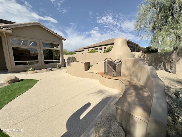 view of side of home featuring a fenced backyard, a patio area, stucco siding, and an outdoor kitchen