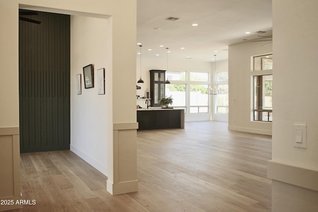 hallway with a sink, light wood-style flooring, recessed lighting, and baseboards