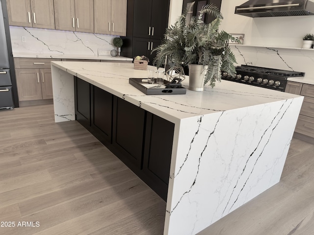 kitchen with wall chimney exhaust hood, light wood-style flooring, a large island, decorative backsplash, and open shelves