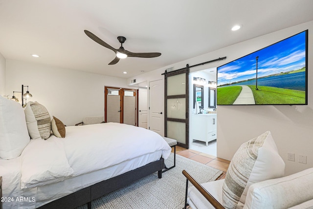 tiled bedroom with a barn door and ceiling fan