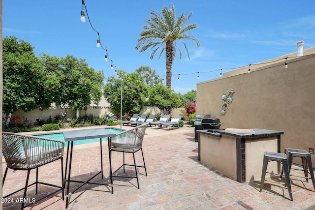 view of swimming pool with a bar, a patio, area for grilling, and exterior kitchen