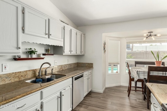 kitchen with baseboards, a sink, white cabinets, dishwasher, and light wood-type flooring