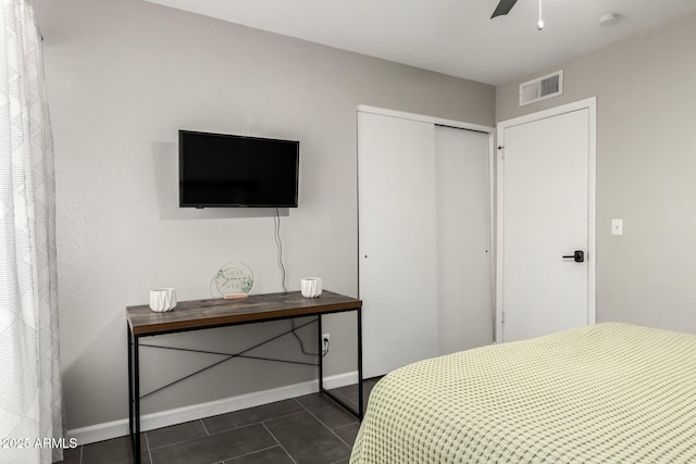 bedroom featuring a closet, visible vents, baseboards, and dark tile patterned floors