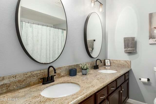 full bathroom featuring double vanity, toilet, and a sink