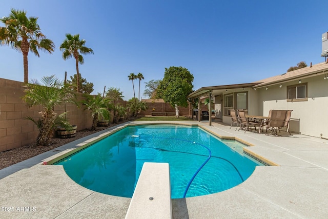 view of pool with a patio area, a fenced in pool, a fenced backyard, and a diving board