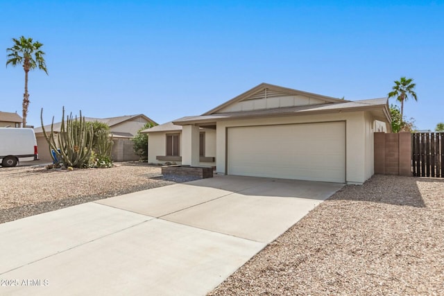 view of front of property with fence, a garage, driveway, and stucco siding