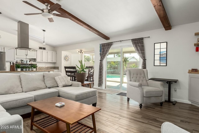 living room with lofted ceiling with beams, wood finished floors, baseboards, and ceiling fan